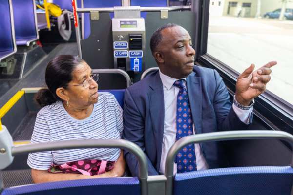 Reverend Preston rides the bus with a passenger.